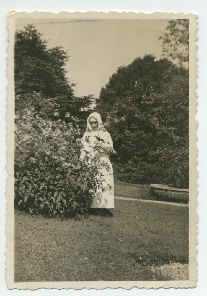 Photographie d'une infirmière (?) cueillant des fleurs pour Hélène Paderewska, malade, dans le parc de Riond-Bosson – extraite d'un album de la famille Obuchowicz
