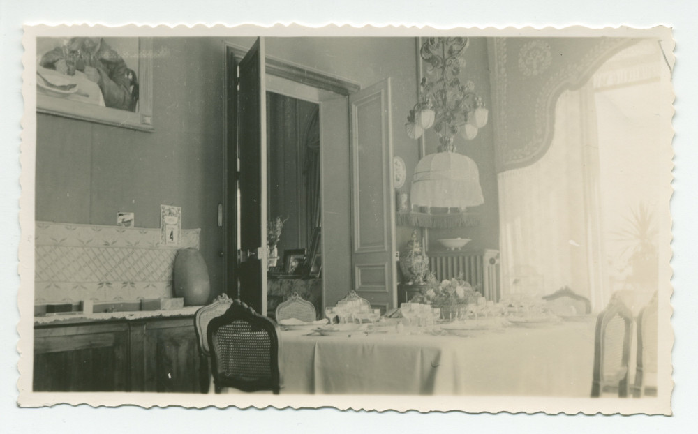 Photographie de la salle à manger de Riond-Bosson, avec la table dressée et la porte ouverte sur le salon (et les photographies dédicacées) – extraite d'un album de la famille Obuchowicz