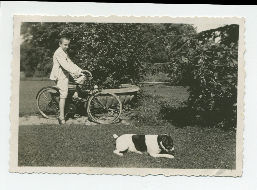 Photographie d'Ignace Obuchowicz (filleul de Paderewski) faisant du vélo dans le parc de Riond-Bosson en compagnie d'un chien, en 1934 – extraite d'un album de la famille Obuchowicz