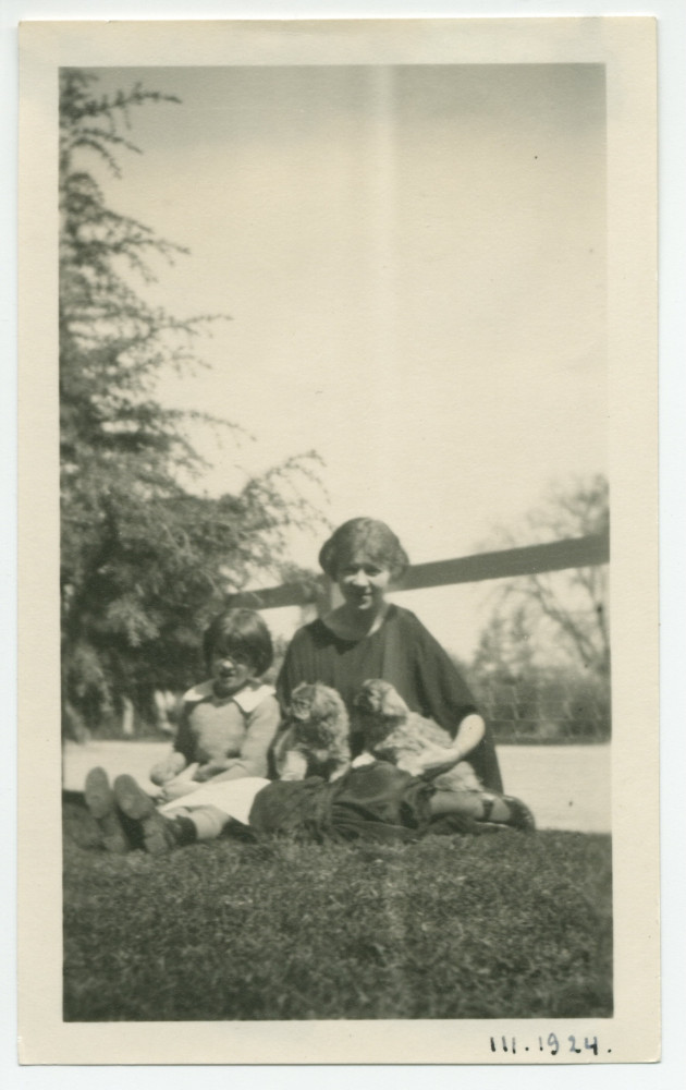Photographie d'Hélène Lübke, secrétaire d'Hélène Paderewska, avec deux chiens dans les bras et en compagnie d'une enfant non identifiée, dans les jardins de l'hôtel de Paso Robles, en Californie, en mars 1924