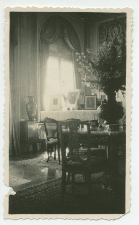 Photographie du salon de Riond-Bosson, avec au premier plan une table garnie d'un gros bouquet, et en arrière-plan un piano à queue avec des photographies dédicacées – extraite d'un album de la famille Obuchowicz