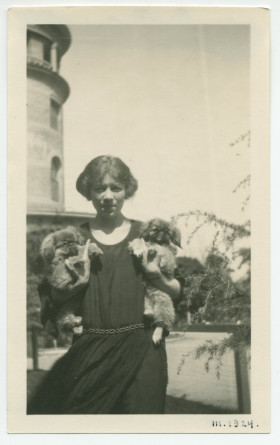 Photographie d'Hélène Lübke, secrétaire d'Hélène Paderewska, avec deux chiens dans les bras, dans les jardins de l'hôtel de Paso Robles, en Californie, en mars 1924