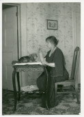Photographie d'Hélène Paderewska parlant à son chien Ping, installé sur une table dans sa chambre à coucher de Riond-Bosson