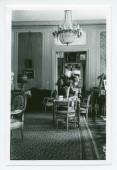 Photographie du salon de Riond-Bosson, prise depuis la salle à manger, avec au fond la porte menant au petit salon (dédié notamment au bridge)